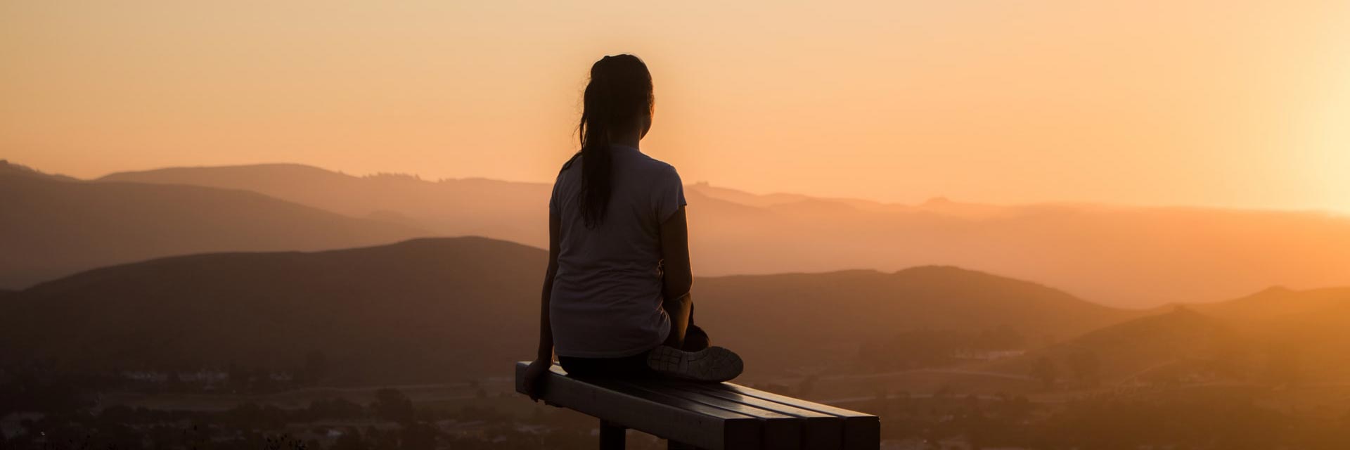 femme assise face au coucher de soleil